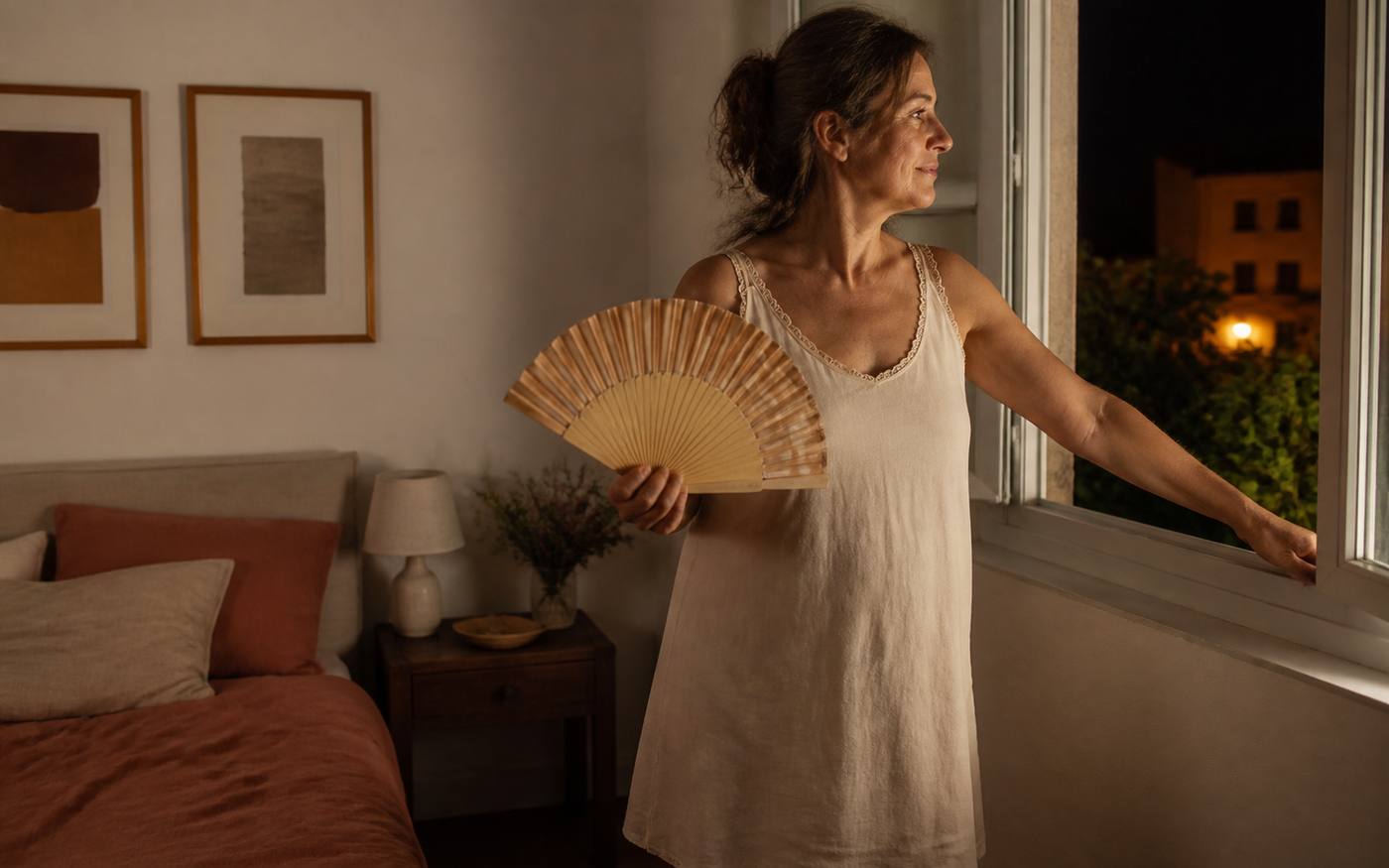 Mujer refrescándose junto a una ventana durante la noche
